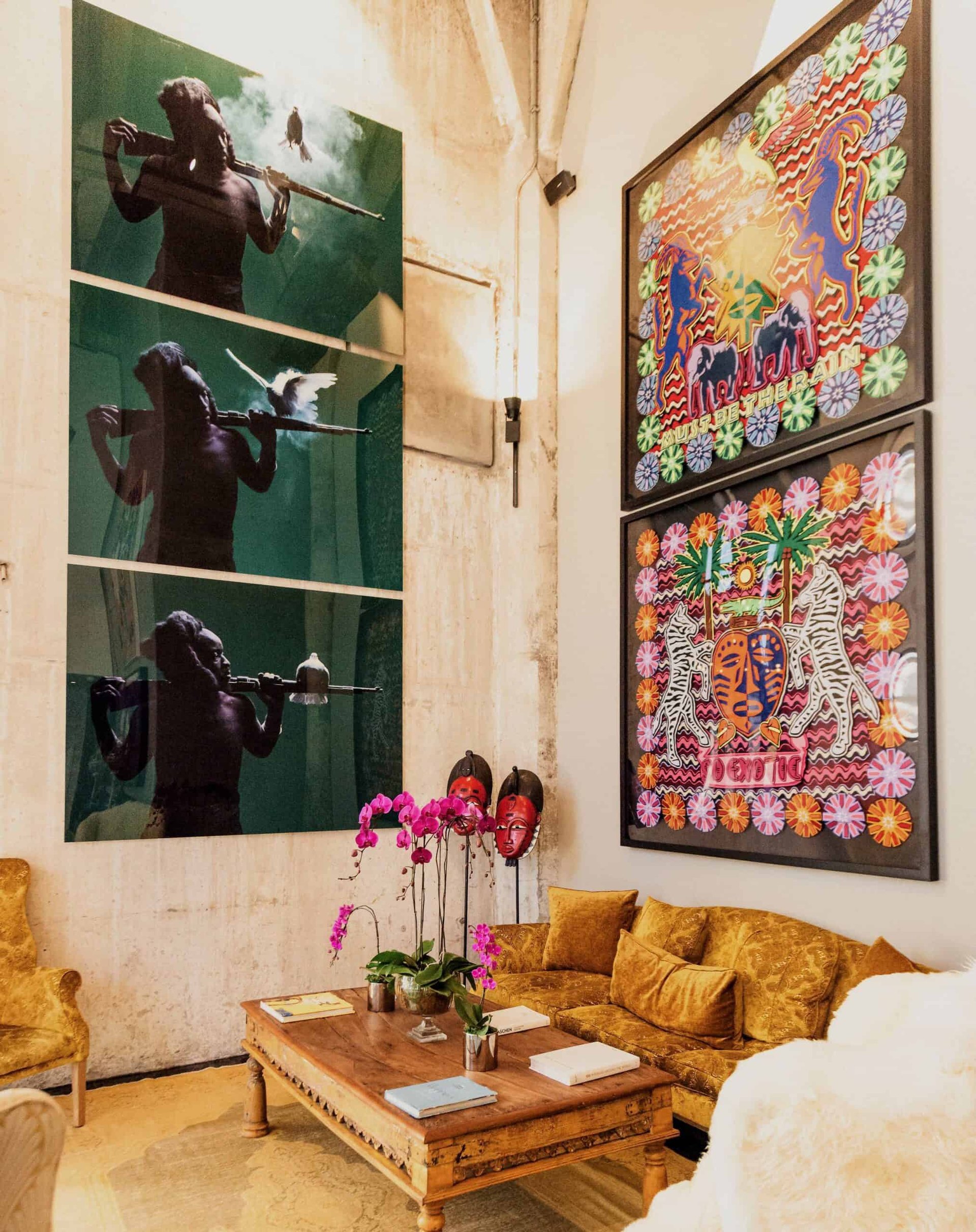 A lounge at The Silo Hotel hung with large artworks, with gold sofas and orchids