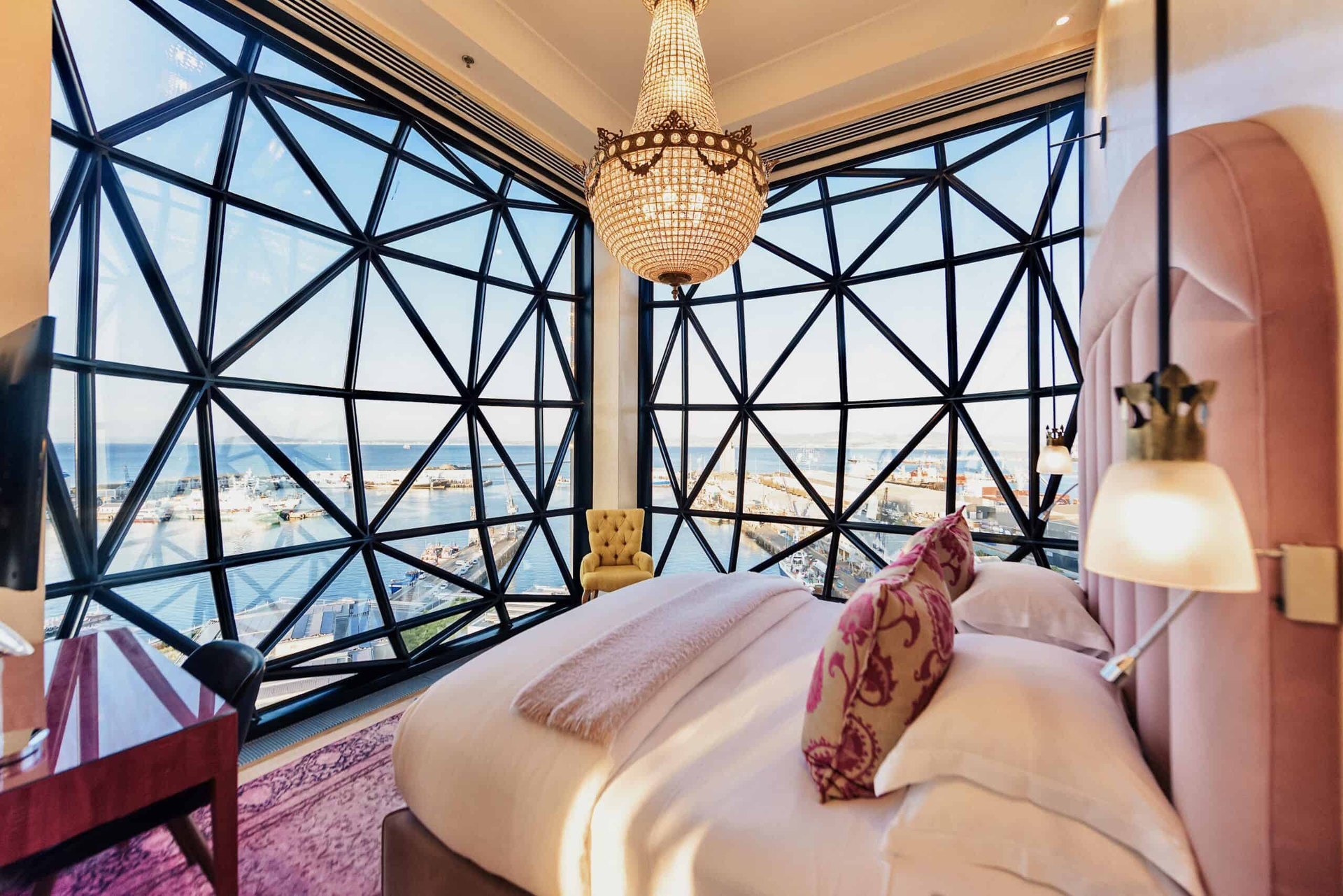 A suite at The Silo Hotel behind its faceted, pillowed-glass windows, with a chandelier and the harbour beyond