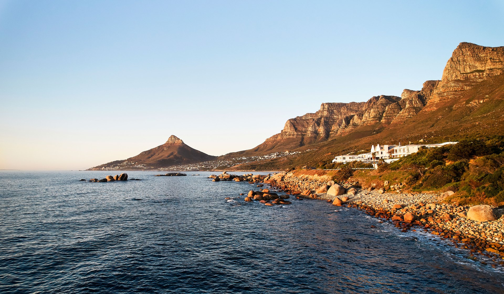 The Twelve Apostles Hotel on the shore at dusk, with Lion’s Head across the bay